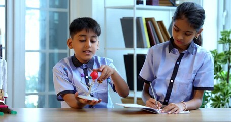 Indian School Kids Learning Solar System Using 3D Model in Classroom While Wearing Uniforms Taking Notes, Engaging in Interactive Science Activity During Academic Session Focused on Space and Planets - Powered by Adobe