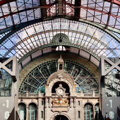 Antwerp Central Station majestic architecture featuring a grand clock and ornate glass roof,...