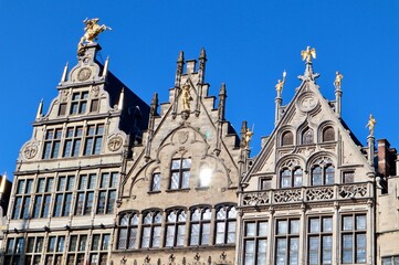 Grote Markt guildhalls displaying renaissance architecture and golden statues under a clear blue...