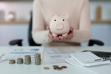 Financial savings. A person holding a piggy bank and reviewing financial documents.
