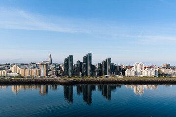 Fototapeta premium Reykjavik cityscape reflecting in still harbor water under clear sky