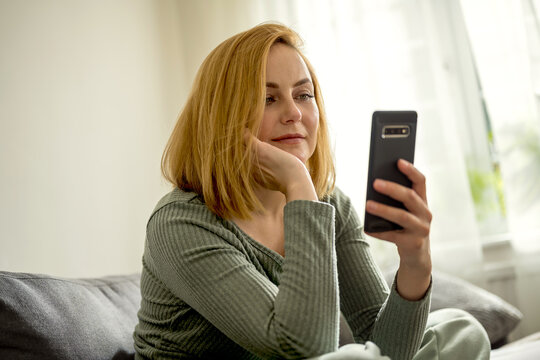 Portrait of a woman holding a smartphone and sitting on a couch