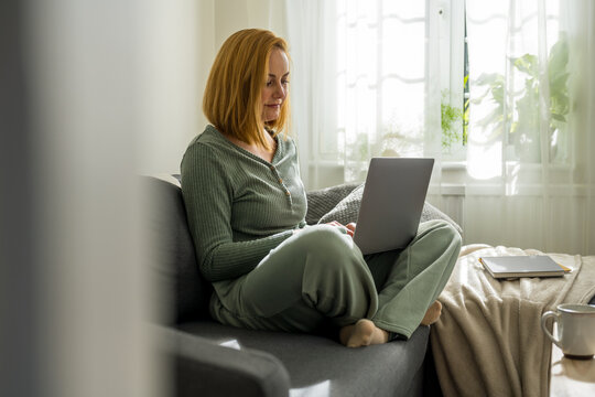 Working from home, woman with laptop sitting on a sofa at home