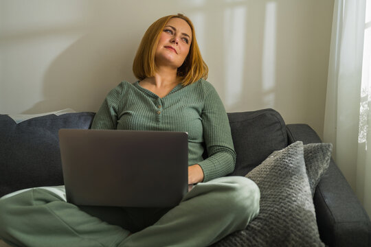 Woman with laptop sitting on sofa, work from home, freelance