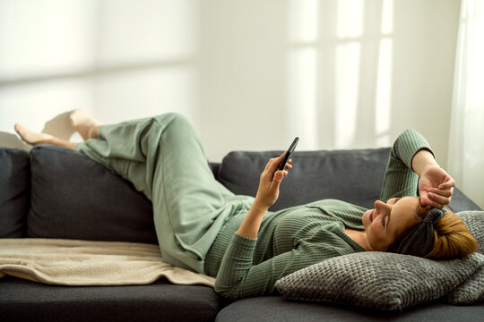 Woman using mobile phone while laying down on  a couch at home