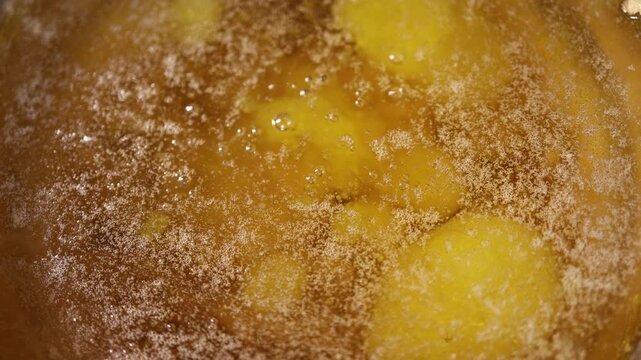 Close up of golden ghee butter boiling with bubbles and fine foam texture showing clarified fat during homemade cooking process under warm kitchen light
