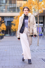 Obraz premium A young brunette in light warm clothes on the streets of an autumn city.