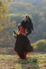 Portrait of a young woman in gothic style clothing in an autumn park. Halloween