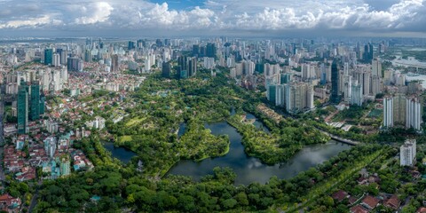 Obraz premium Aerial View of Urban Skyline Surrounded by Green Parks and Water Bodies Beneath Cloudy Sky