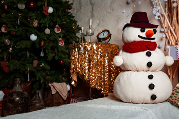 Beautiful snowman toy stands near a decorated Christmas tree on New Year's eve. St. Nicholas Day. Present. Time of holidays and miracles. Background.