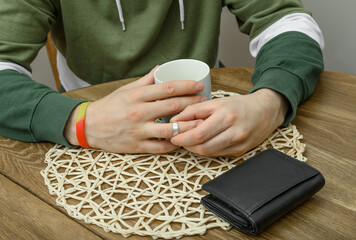 An impatient man fiddling with his wedding ring waits by a cup of coffee © Paweł Kacperek