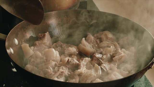 A chef is frying dry pot lamb in an iron pan