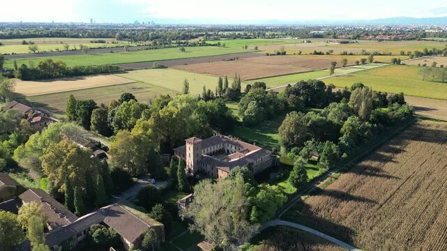 Aerial panorama of a historic castle landscape near Milan, Italy, showing medieval architecture, surrounding moat waters, and rural scenery.