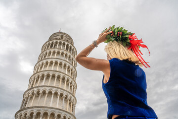 Graduate woman under the Leaning Tower in Pisa wearing traditional Italian laurel wreath for laurea