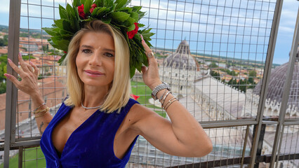 Proud graduate girl celebrating academic success with laurel garland near Pisa Tower landmark