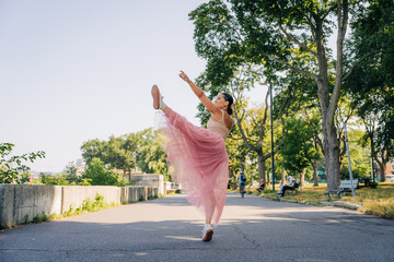 Ballerina dancing en pointe elevating leg in urban park