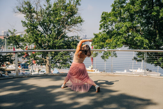 Woman performing contemporary dance pose outdoors near marina
