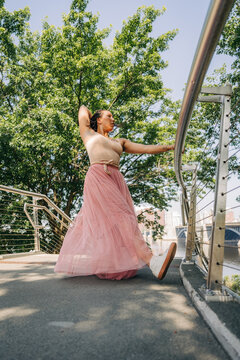 Woman dancing urban park bridge wearing pink skirt