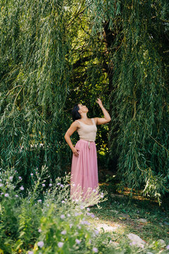 Woman wearing pink skirt under weeping willow tree