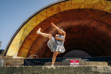 Energetic woman performing modern dance on outdoor bandshell stage
