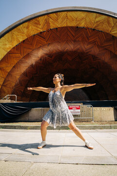 Woman practicing yoga warrior pose at urban bandshell