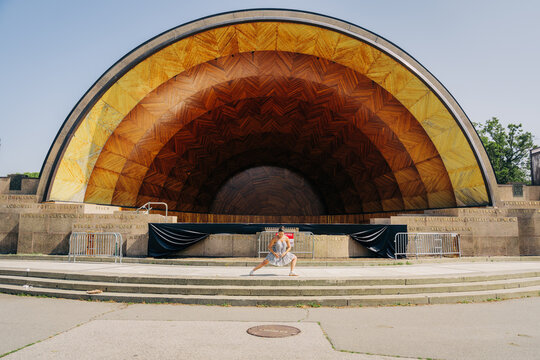 Woman performing a yoga pose on a stage at hatch memorial shell