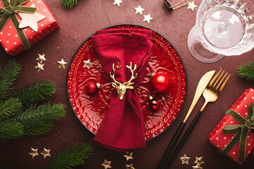 Christmas celebration table setup. Christmas table setting, empty red plate with napkin, wine glass and Christmas decorations top view