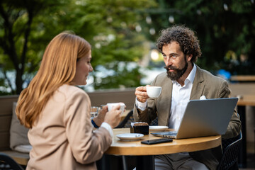 Business people having coffee break outdoors and discussing work using laptop