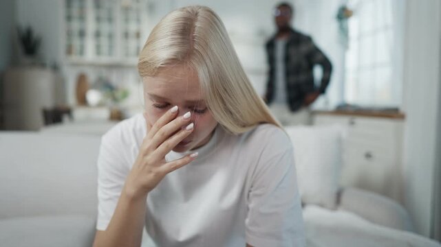 Young beautiful blonde woman crying when quarreling with husband at home. Domestic violence and love relationship problems, abusive relationships and psychological violence, chronic depression