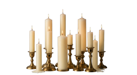 Collection of lit & unlit cream candles in brass candlesticks on black backdrop