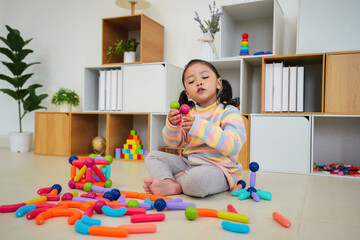 toddler girl playing colorful magnetic construction toy