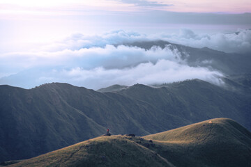 A man with his tent is taking a view of Mountain Range view point in Myanmar (Burma) with sea of cloud (Mulayit Taung) and sunrise