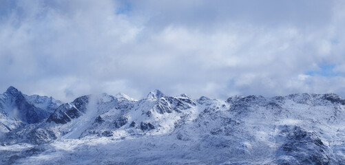 Majestic snow-covered mountain range under a dramatic sky, showcasing rugged peaks and serene winter landscape, inviting exploration and adventure in nature's beauty