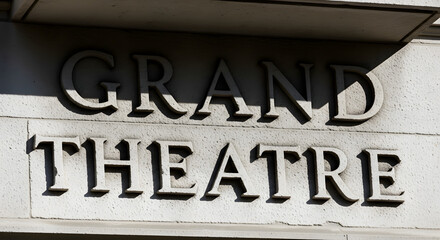 Obraz premium The words Grand Theatre carved in stone on the facade of a historic building with strong shadows