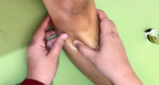 Close-up of acupressure massage on the lower knee using thumb circular motion to ease side effects of anti-tuberculosis drugs. Health and therapy concept