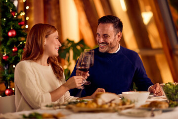 Couple Toasting With Wine During Festive New Year Dinner Near Christmas Tree