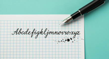 Elegant handwritten cursive alphabet on graph paper with fountain pen and ink splatters for calligraphy practice