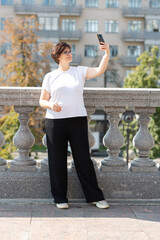 A middle-aged woman records videos on her phone, blogger, video call