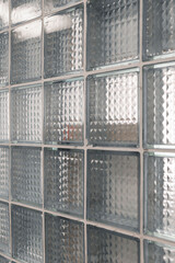 A close-up view of a glass block wall highlights the textured surface and transparency, enhancing the bright atmosphere of the contemporary room