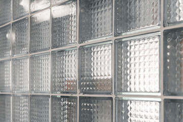 Translucent glass blocks form a modern wall, allowing light to filter through while adding texture and depth to the space. The design enhances the atmosphere with geometric shapes