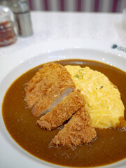Japanese Pork Cutlet Katsu Curry with Fluffy Omurice Omelette on White Plate