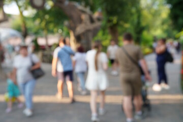 Blurred background. People are walking in the city park.