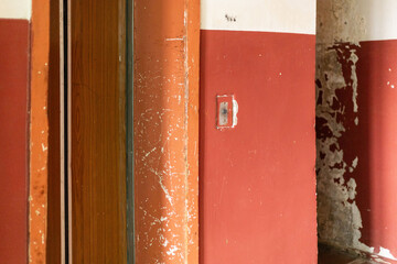 The interior of an old house reveals walls in deteriorating condition, marked by peeling paint and...