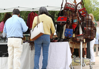 Fototapeta premium Puesto de cuero en mercadillo de ropa de piel, bolsos, marroquinería y complementos en feria con personas de espaldas comprando al aire libre