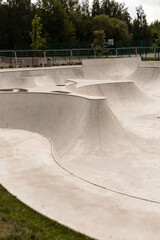 A modern skatepark features smooth, flowing concrete structures with various ramps and bowls, ideal...