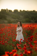 Woman in white dress standing in a poppy field.