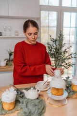 Woman Easter kitchen preparing traditional kulich cakes on table for holiday