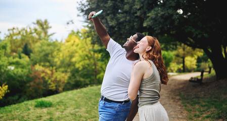 Young couple taking selfie and laughing together outdoors
