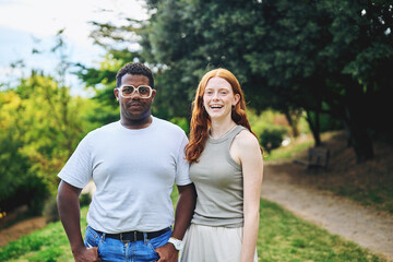 Obraz premium Portrait of a young couple smiling together outdoors in a park