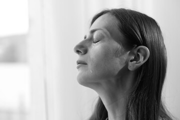 Woman crying at home, closeup with space for text. Black and white effect